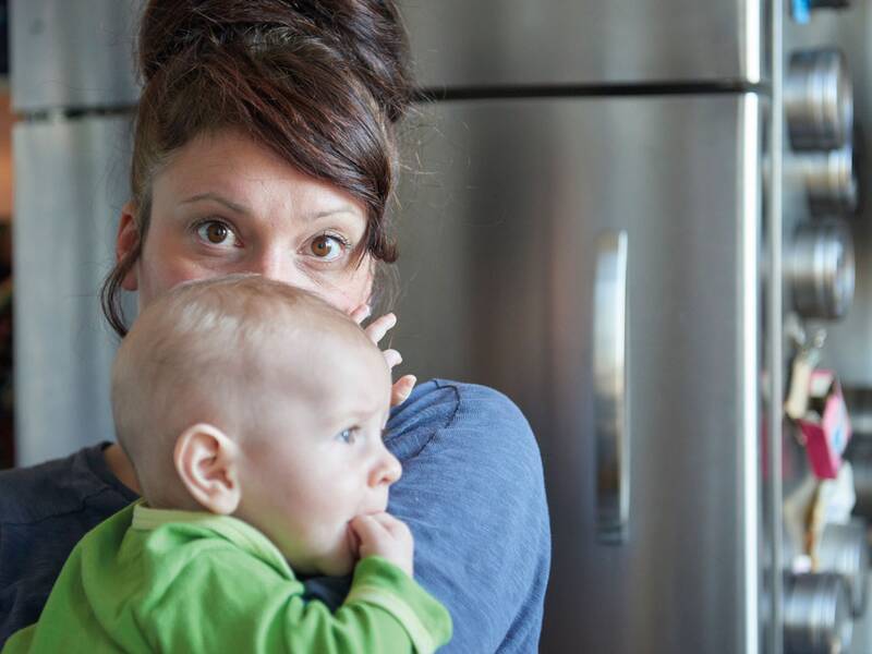 Eine Frau hält ein kleines Baby im Arm, das neugierig zur Seite schaut.