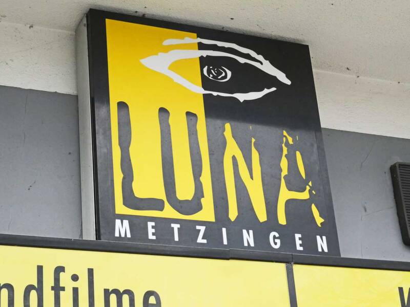 Ein Schild mit der Aufschrift "LUNA METZINGEN" zeigt ein stilisiertes Auge im oberen Bereich.