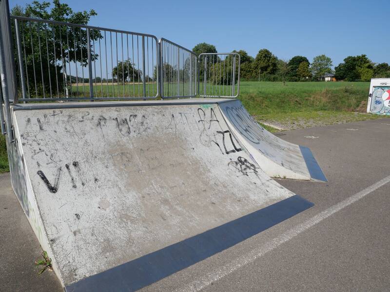 Quarterpipe mit Geländer, deren Oberfläche stark abgenutzt und mit Graffiti versehen ist.