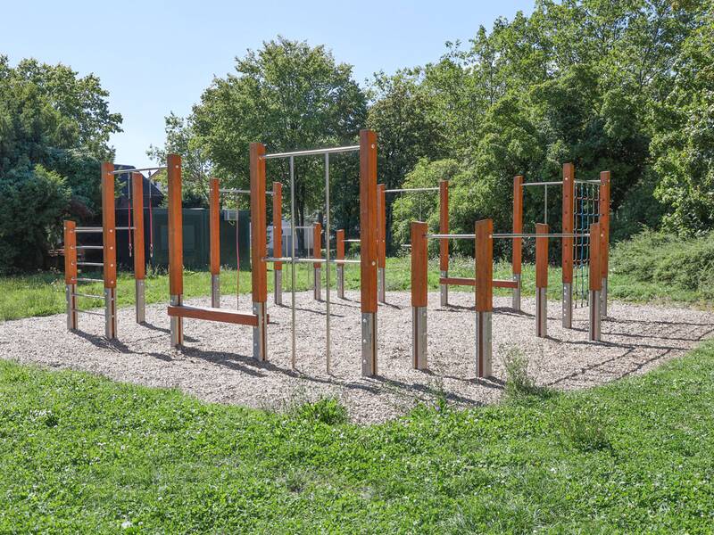 Übersicht über eine moderne Kletteranlage mit Holz und Metall auf Rindenmulch.