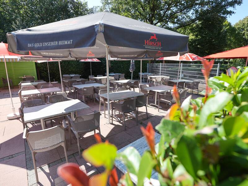 Freibad Metzingen, Sitzbereich am Kiosk, Sitzgruppen mit Tischen und Stühlen unter Sonnenschirmen