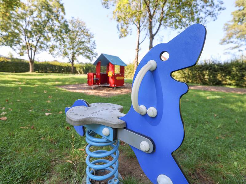 Freibad Metzingen, Spielbereich, kleines Spielhaus im Hintergrund, Schaukeltier im Vordergrund