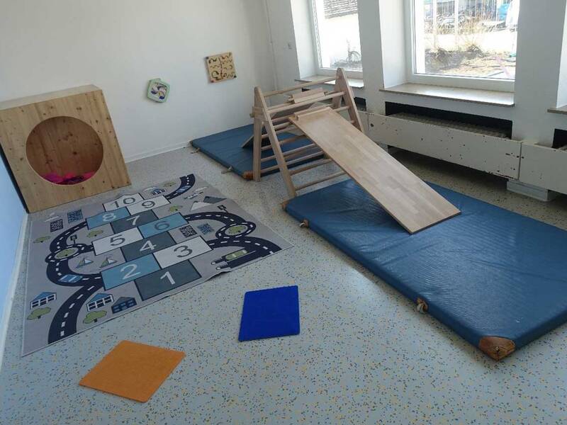Ein Bewegungsraum mit Matte und Holzgeräten zum Klettern.