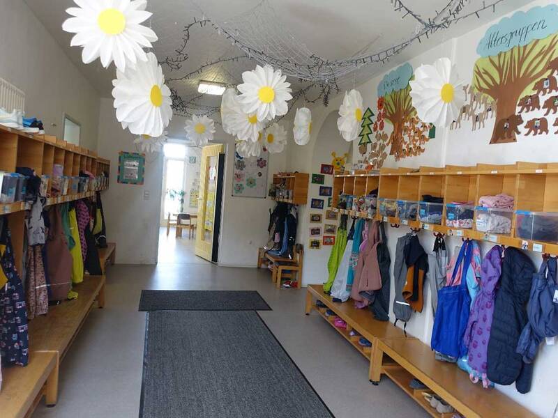 Eingangsbereich des Kindergartens mit einer Holzgarderobe an beiden Seiten des Flurs.