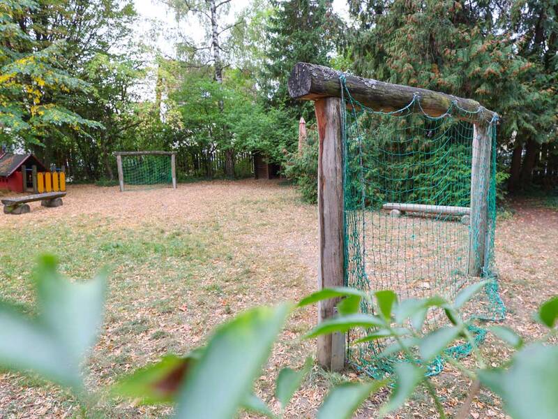 Zwei kleine Holz-Tore und ein Spielhäuschen auf einer naturbelassenen Wiese