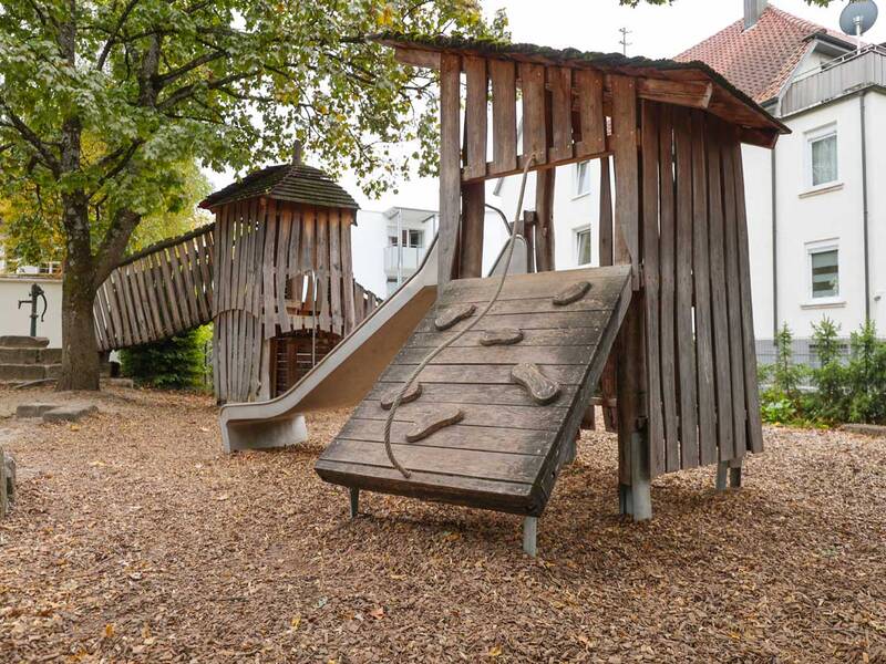 Zwei verbundene Holztürme mit Kletterwand, Rutsche und Seil.