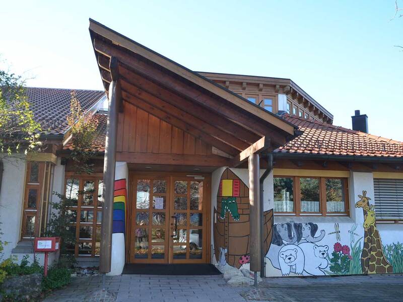 Ein Gebäude mit einem Holzdach und bemalten Wänden, die bunte Tiermotive wie Giraffen und Eisbären zeigen.