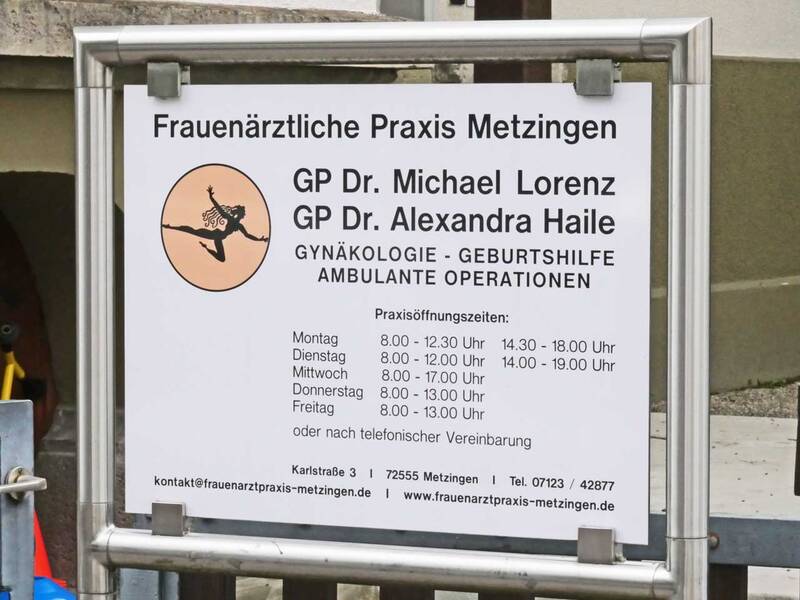 Ein Schild der Frauenärztlichen Praxis Metzingen zeigt die Namen der Ärzte, die Fachrichtungen und die Öffnungszeiten.